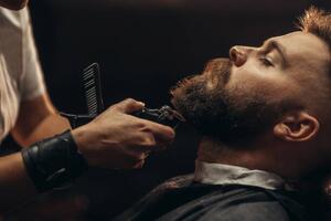 Fotografija Young bearded man getting beard haircut, zamrznutitonovi