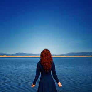 Umjetnička fotografija Redhead in blue dress faces rippled lake, Anna Gorin, (40 x 40 cm)