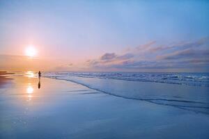 Umjetnička fotografija Person walking on beach at sunrise, Shannon Fagan, (40 x 26.7 cm)