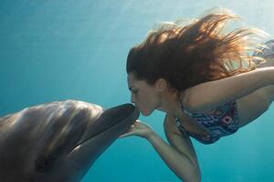 Fotografija Young Woman Kisses Dolphin Underwater, Sunbeams, Justin Lewis, (40 x 26.7 cm)