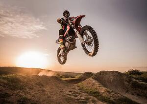 Fotografija Motocross rider performing high jump at sunset., skynesher