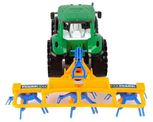 Zeleni traktor s narančastim i plavim pogonom trenja grablja